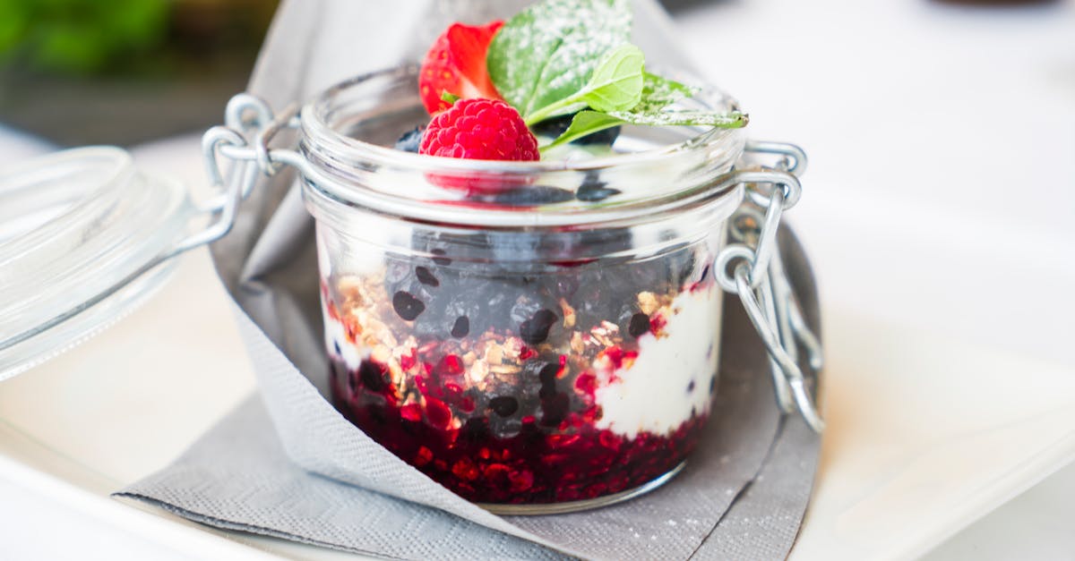 Homemade berry dessert with cream and mint in a glass jar, perfect for breakfast.