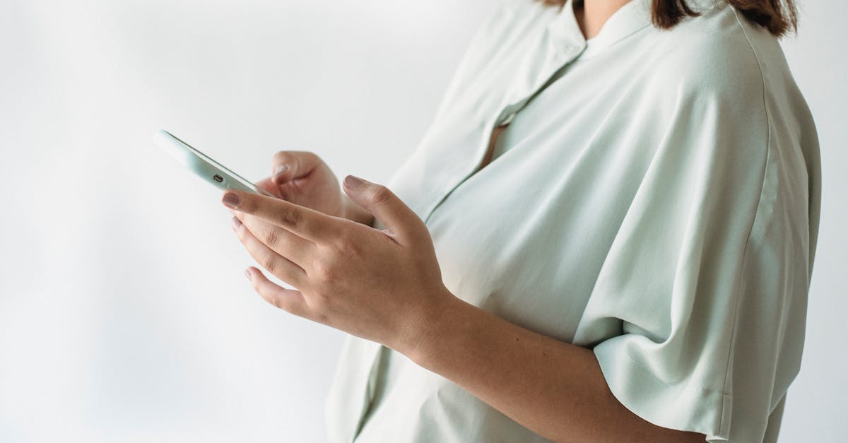 A woman in a light shirt using a smartphone indoors, focus on technology interaction.