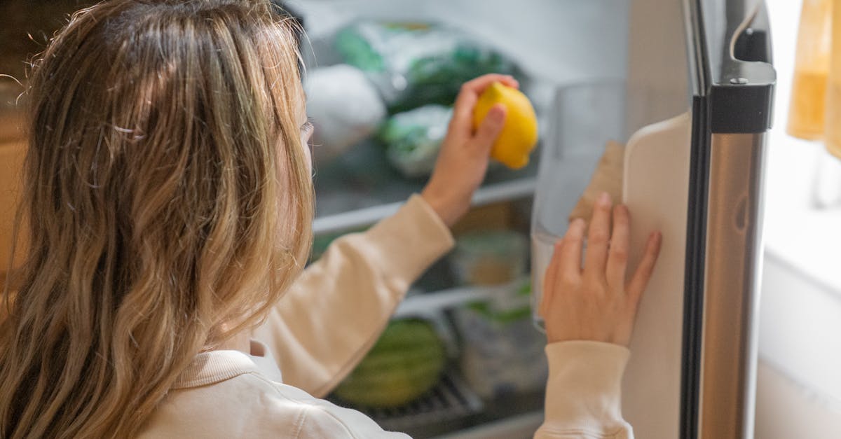 Woman reaching for a lemon in the fridge, illustrating healthy living habits.